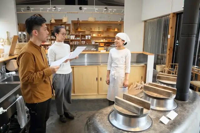 かまどの前で丁寧に説明してくれる山下さん（右）。