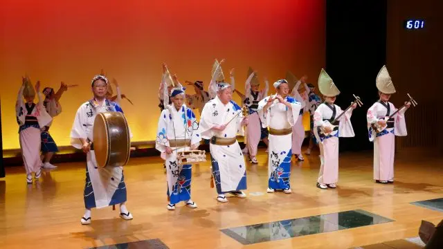 伴隨著熱鬧的囃子音樂伴奏，舞者邊跳著阿波舞邊上台。舞台一下子變得華麗起來。