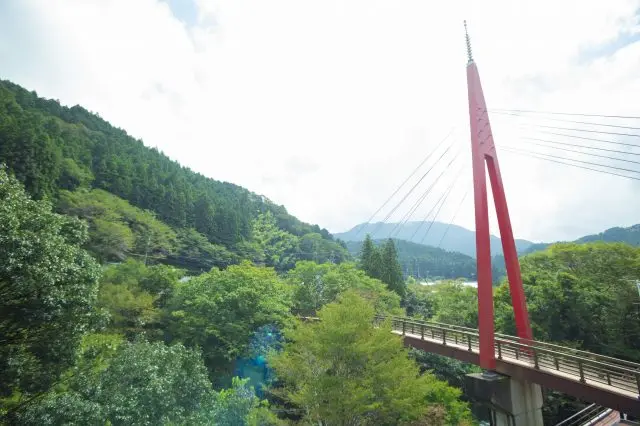 Go across a red truss bridge over the pure Umatate River