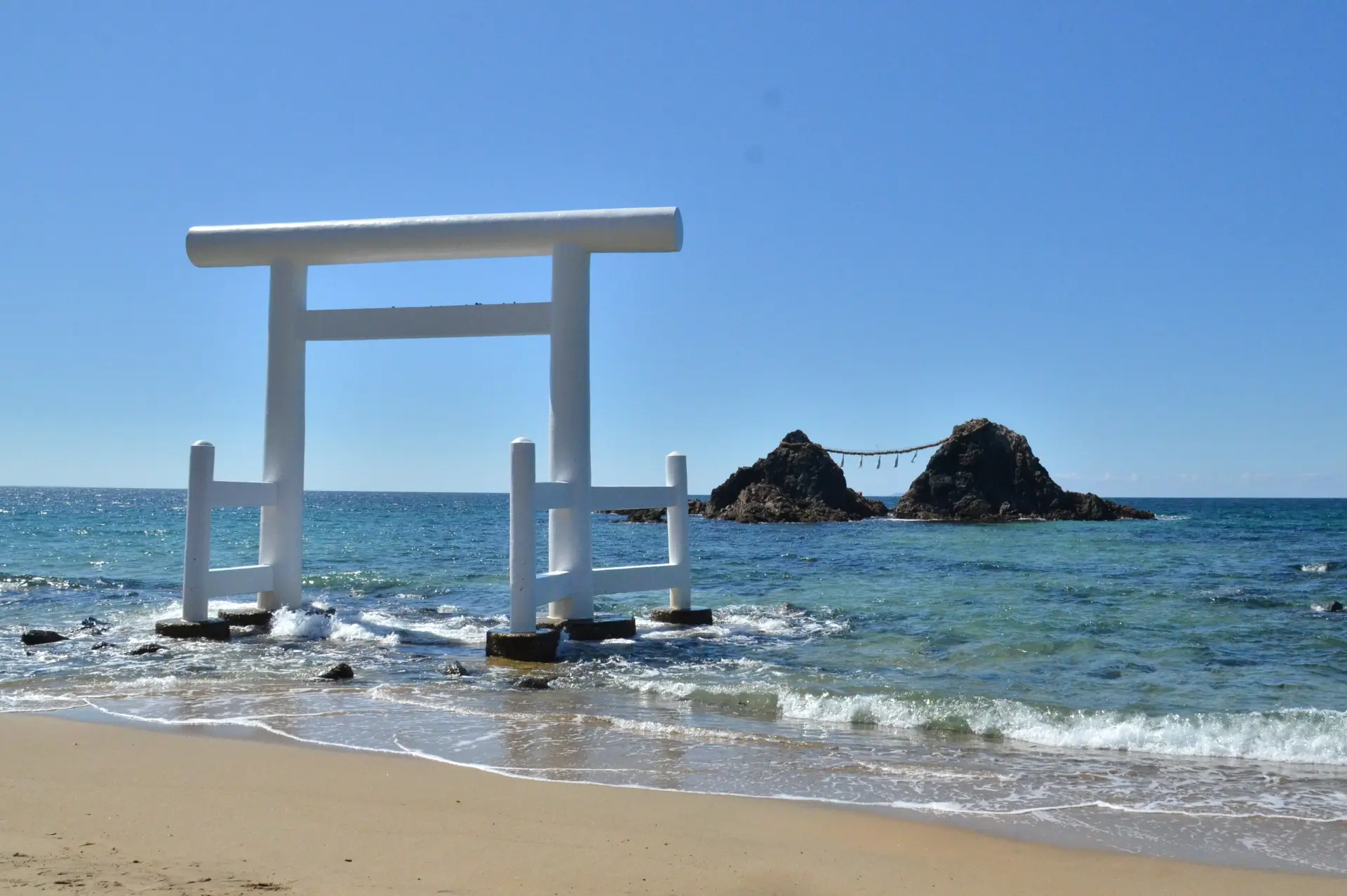 巨大な夫婦岩の間に夕日が沈む、人気の絶景スポット