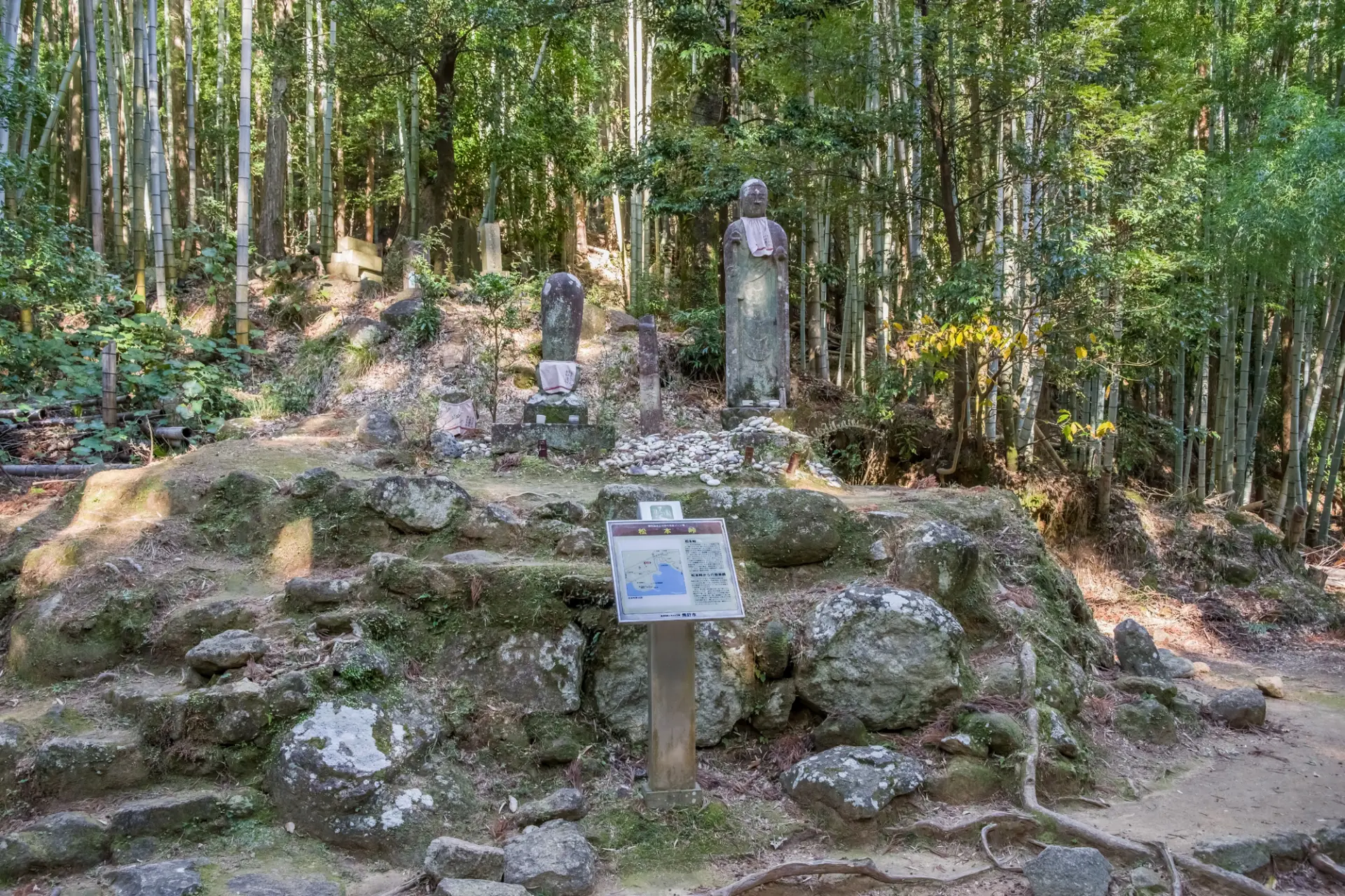 A large Jizo statue welcomes travelers at bamboo-lined Matsumoto Pass