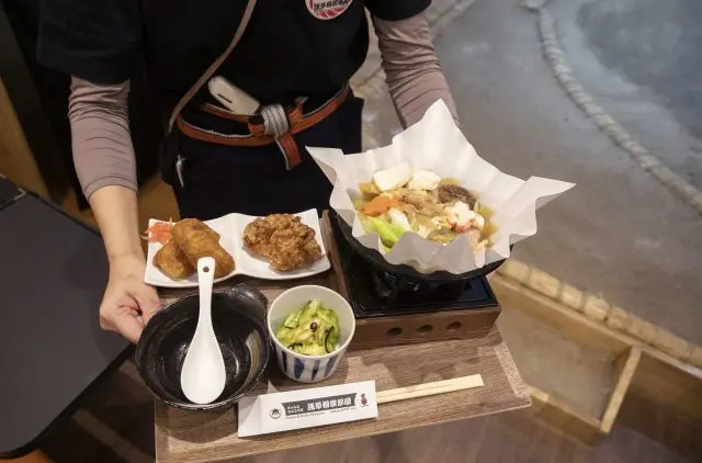 The chanko nabe is served in a tray style, allowing solo diners to enjoy the experience. The karaage is crispy, and the inari sushi is juicy. The pickled cabbage serves as a perfect palate cleanser between bites.