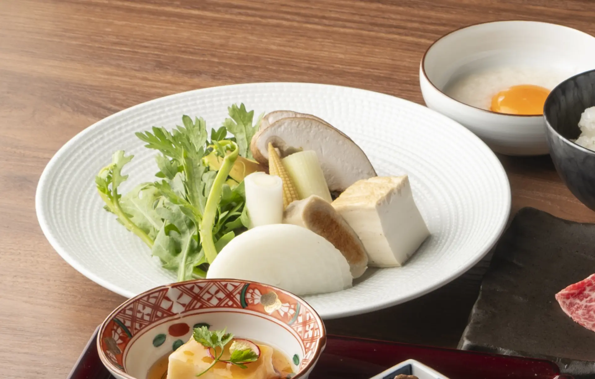 At the time of coverage, dishes included Kaga vegetables such as kinjiso, shiitake mushrooms from Tokushima, and fresh kikurage mushrooms from Ishigaki Island.