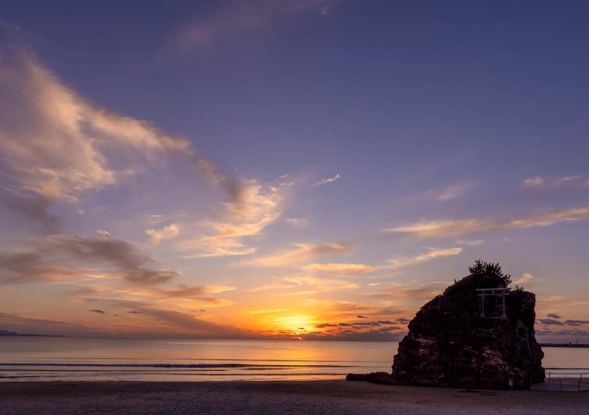 夕焼けに染まる稲佐の浜と沖の弁天島