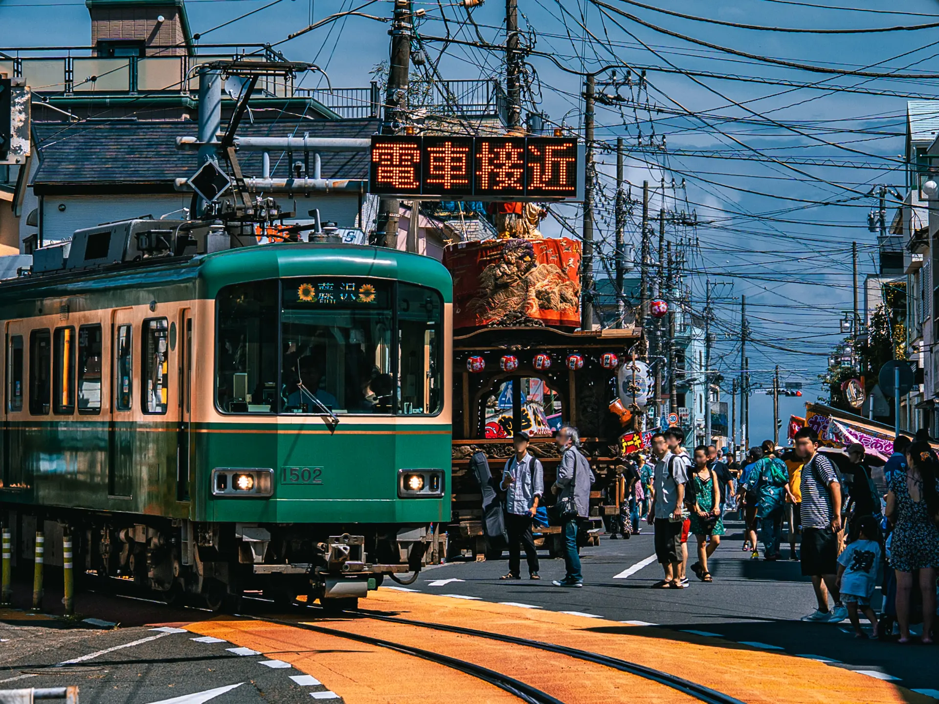 祭りの賑わいの中を路面電車が走る珍しい光景