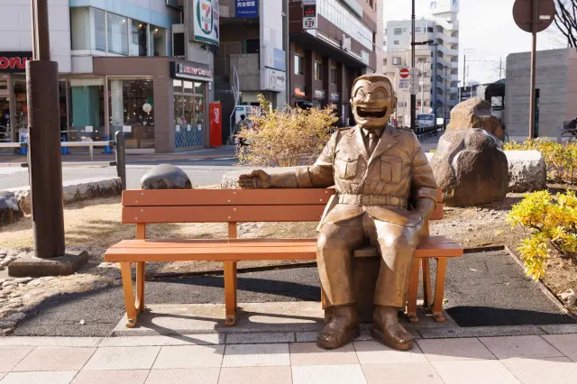 坐在「歡迎來到龜有兩兄像」身旁拍攝紀念照