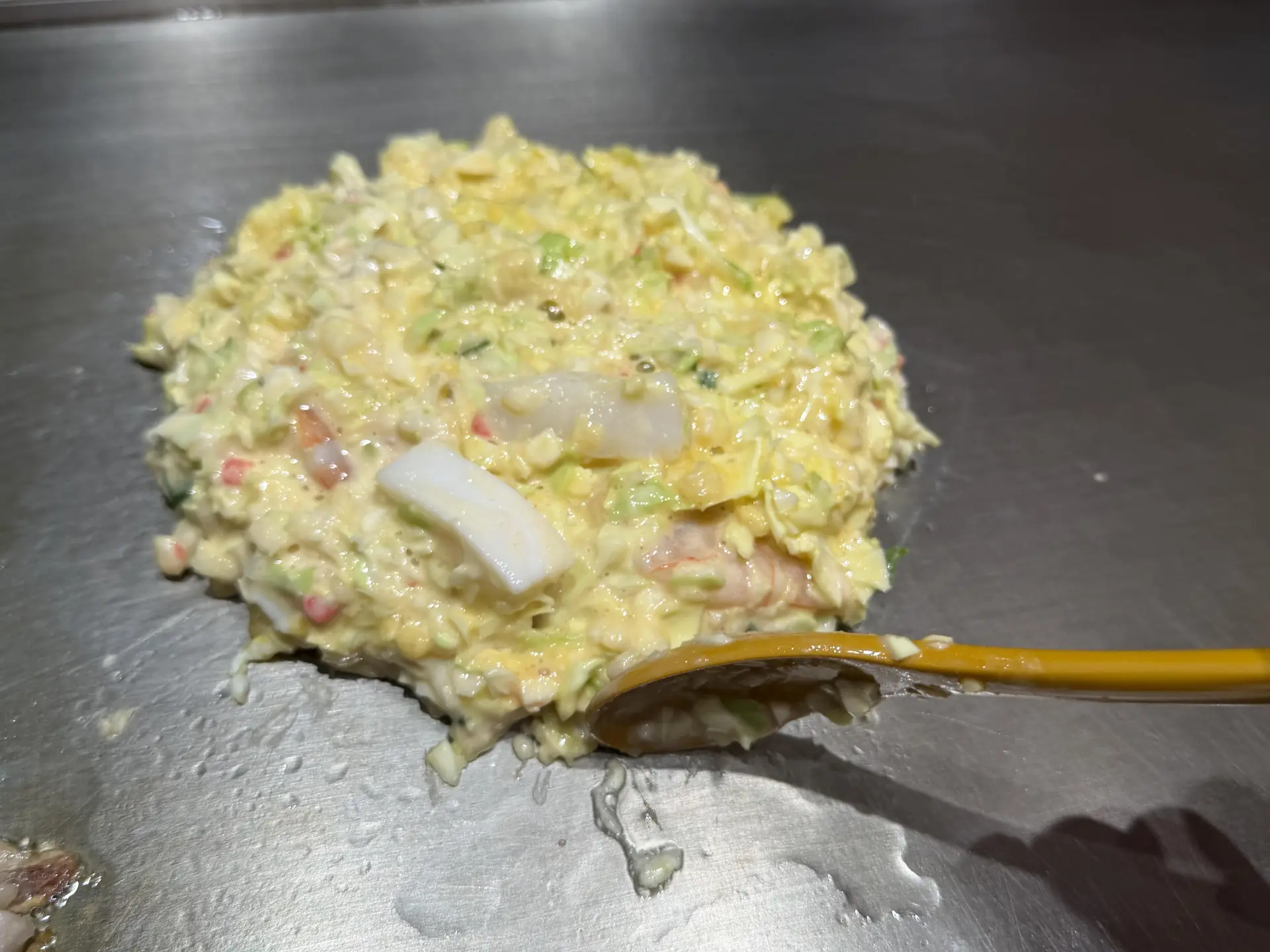 鉄板に生地をのせ、スプーンで形を丸く整える