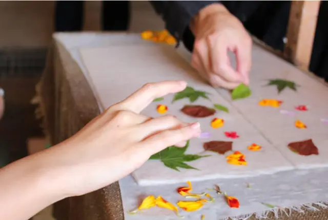 在抄好的和紙上排列葉片與花瓣來製作圖樣的工序