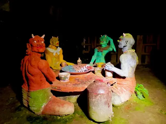 洞窟内に並ぶ鬼の像の展示。色彩豊かな鬼たちが円卓を囲むユニークな造形