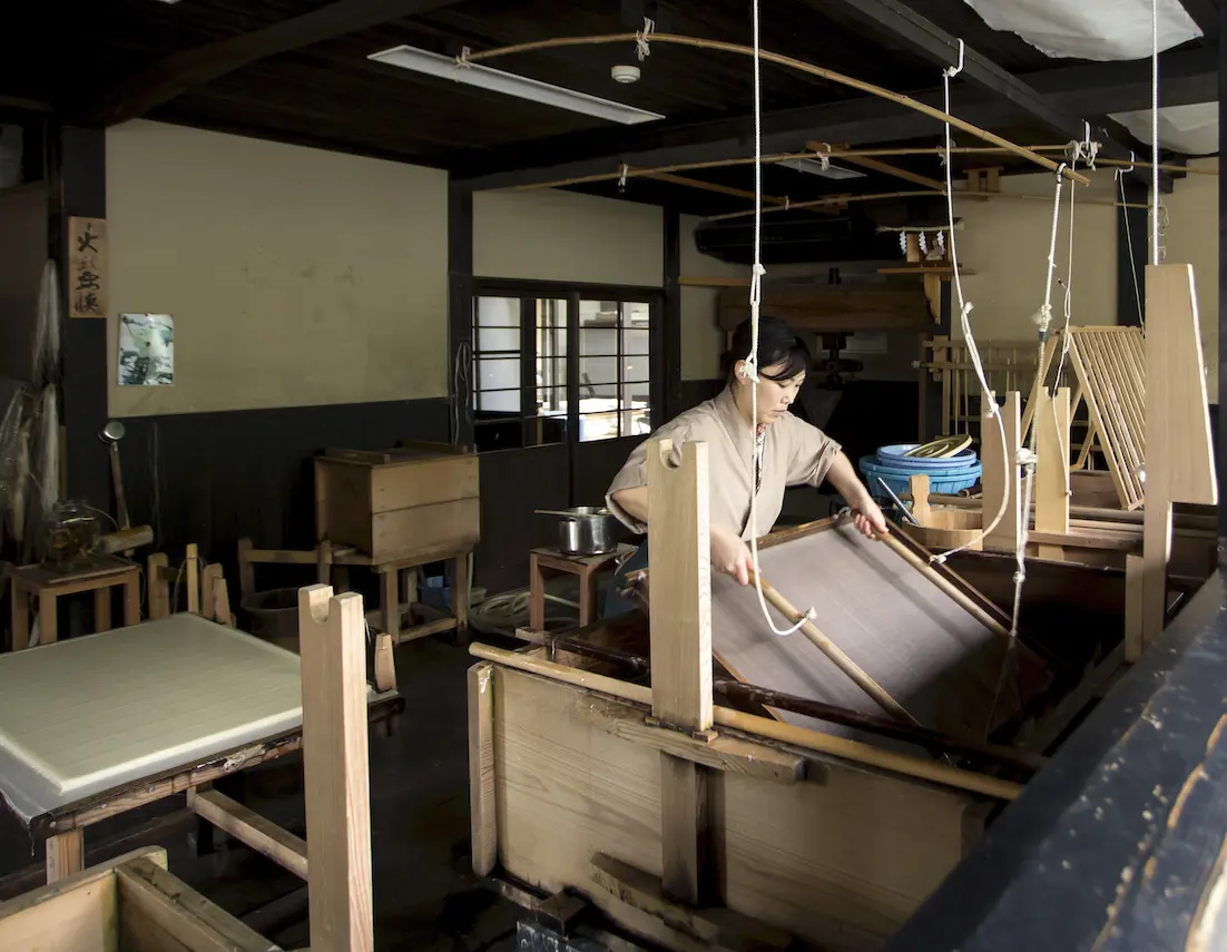 木製の紙漉き道具を使い、和紙を漉く作業を行う職人の様子
