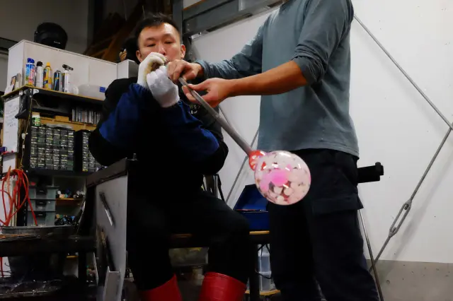 加熱したガラスを竿の先で回しながら成形する作業の様子