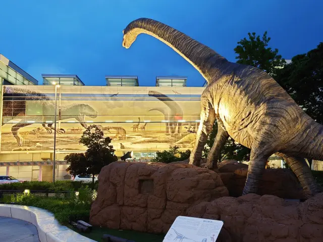 夜間在燈光照映下的巨大恐龍紀念物，氣勢十足