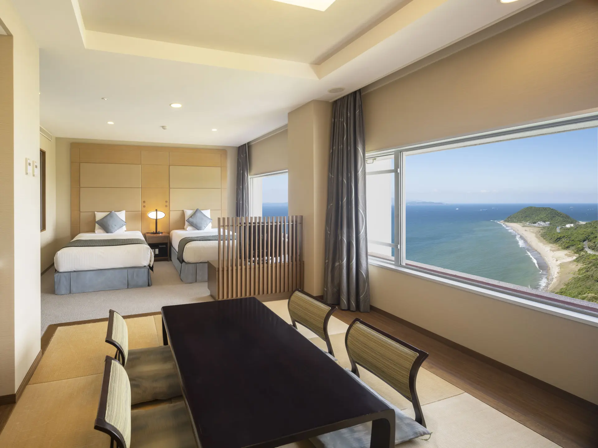大きな窓の向こうに海岸線と海が広がる客室。和洋室などタイプも豊富