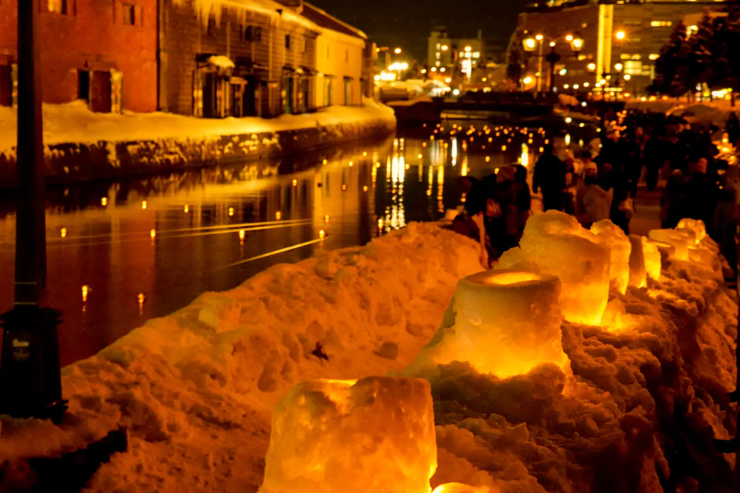 ริมคลองมีเทียนหลากหลายแบบเรียงราย ส่องแสงให้เมืองงดงาม