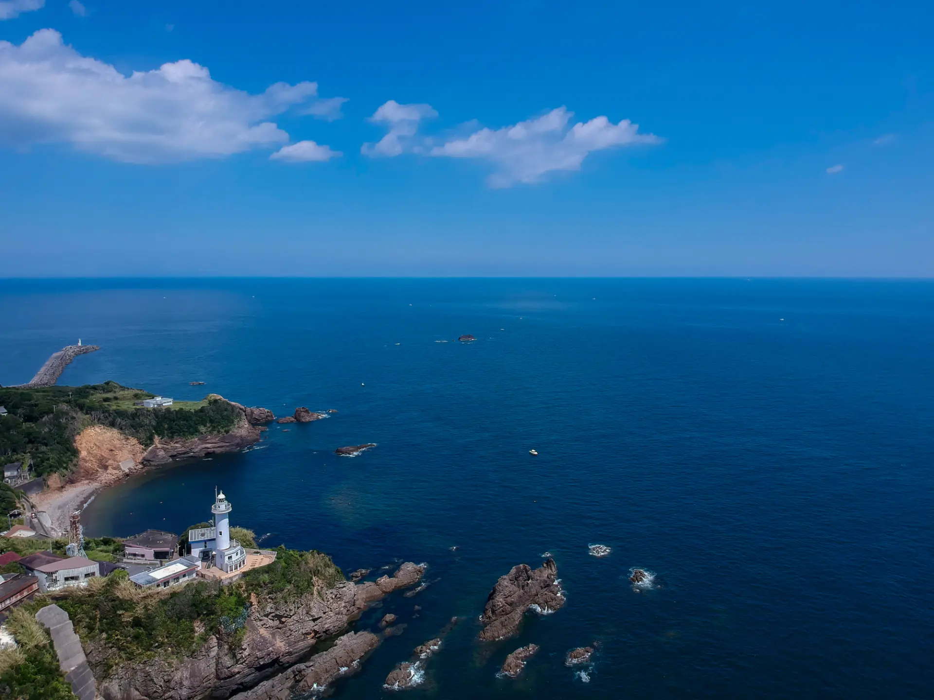 岬の先端に立つ灯台の風景。開けた視界の先に広がる大海原の絶景