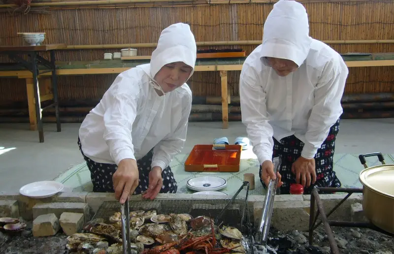 白装束の海女さんが炭火で調理し、焼きたてを囲みながら話を聞く時間が楽しい