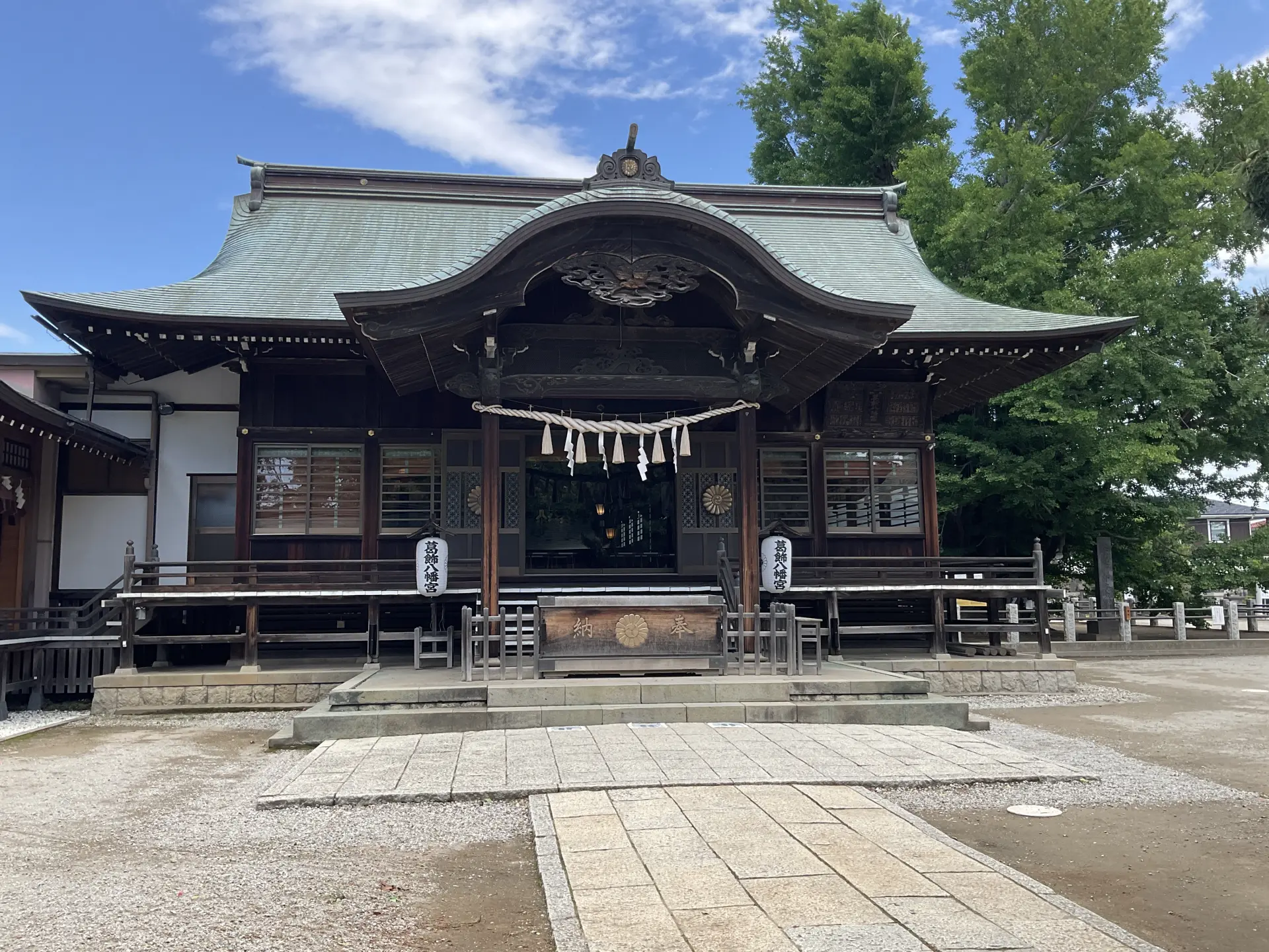 拝殿正面と屋根の反りが印象的な社殿外観。石畳の参道の先に静かな境内が広がる