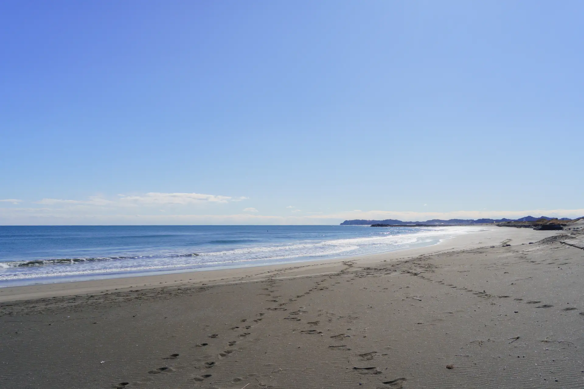 延々と続く砂浜。視界の先まで遮るものがなく、水平線の広がりを感じる風景