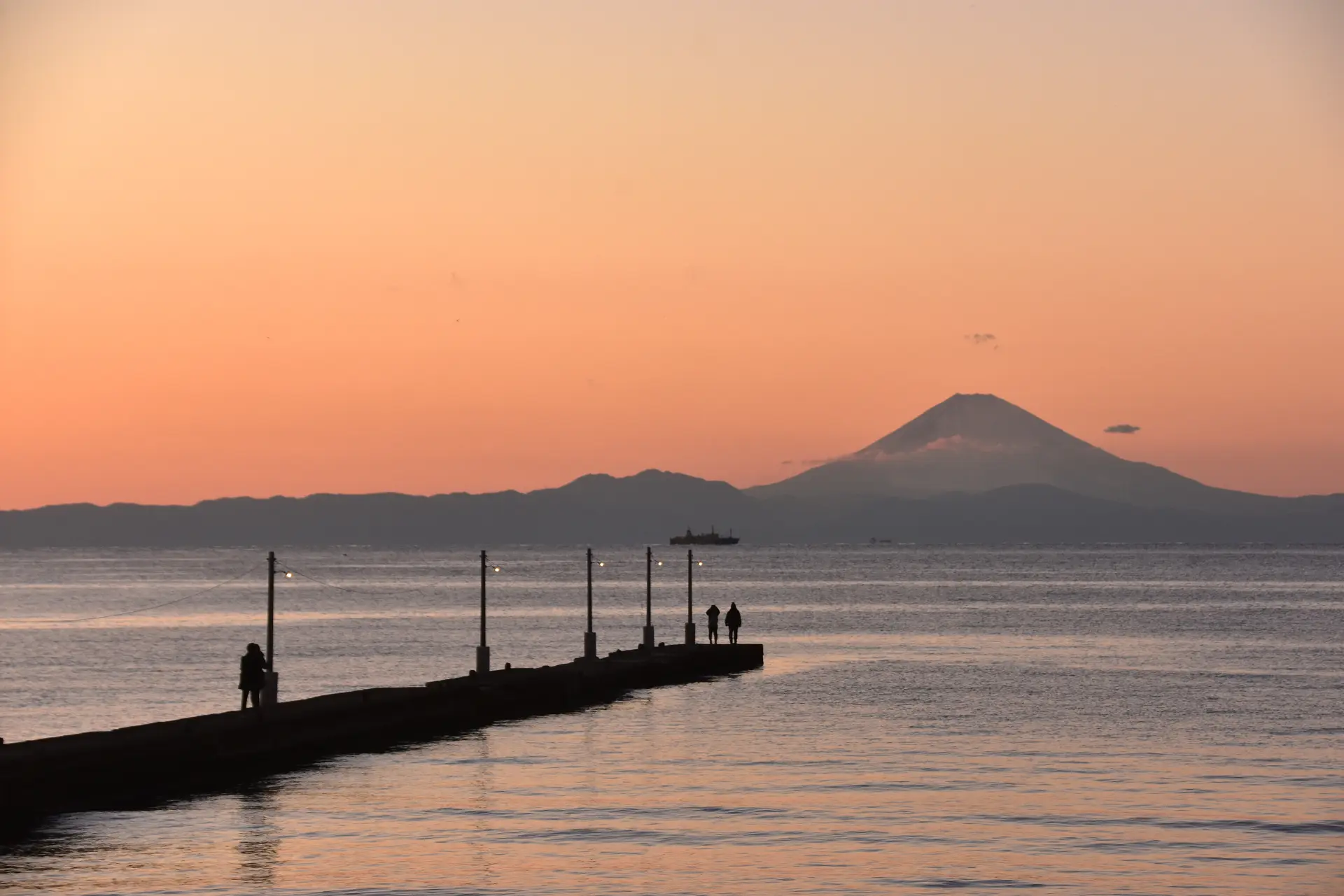 海へまっすぐ伸びる木製の桟橋。その先にはうっすらと富士山のシルエットが見える
