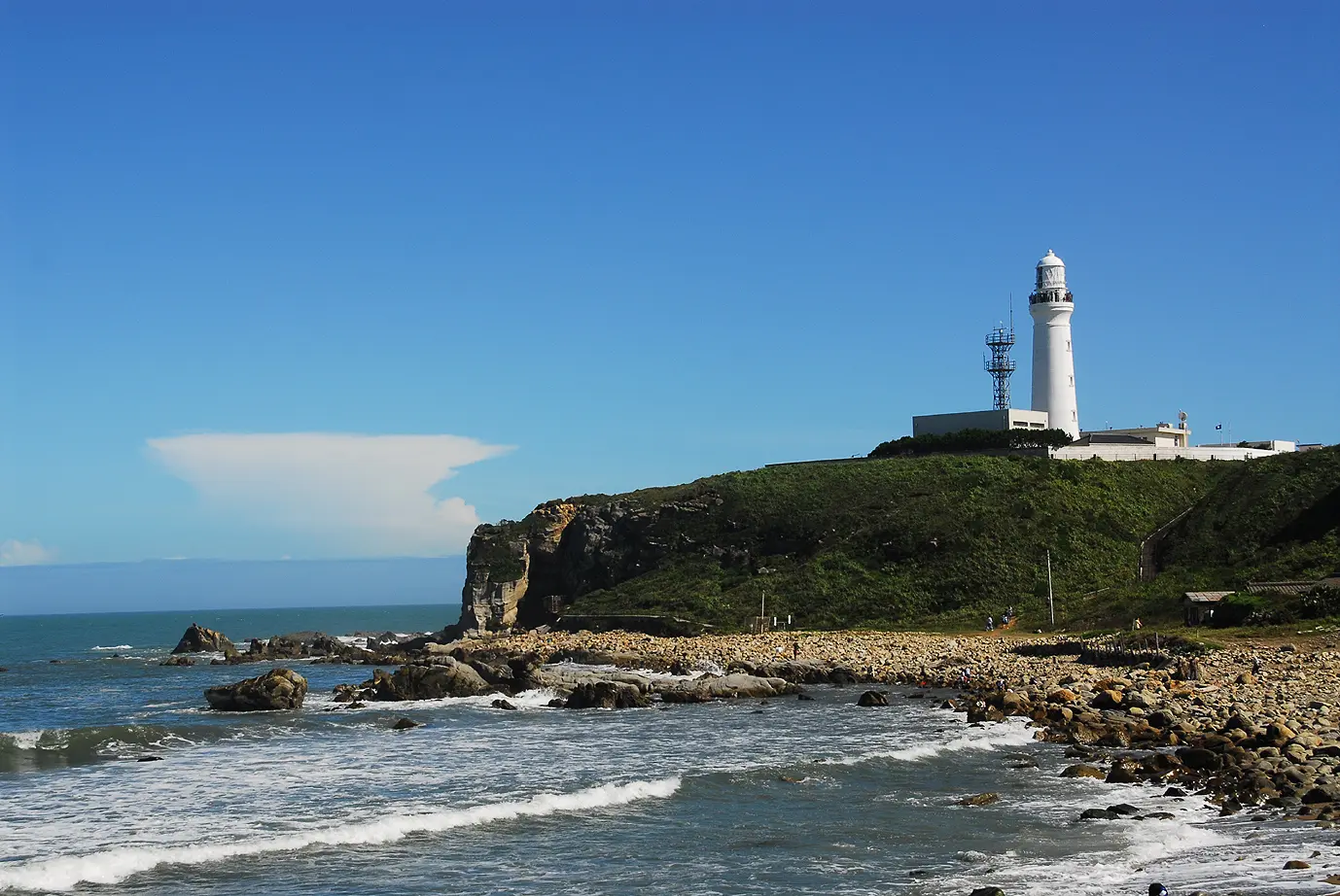 波が打ち寄せる海と高台の灯台が印象的な景観を作り出す