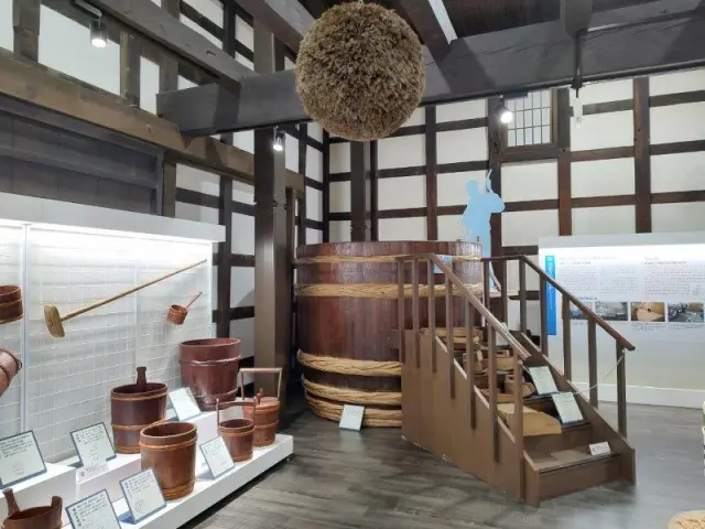 酒造りの道具や大型の仕込み桶が並ぶ展示空間。木桶と用具が整然と並ぶ