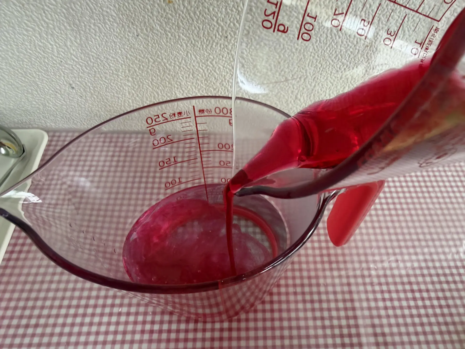 將粉紅色色水倒入裝有糖蜜的容器