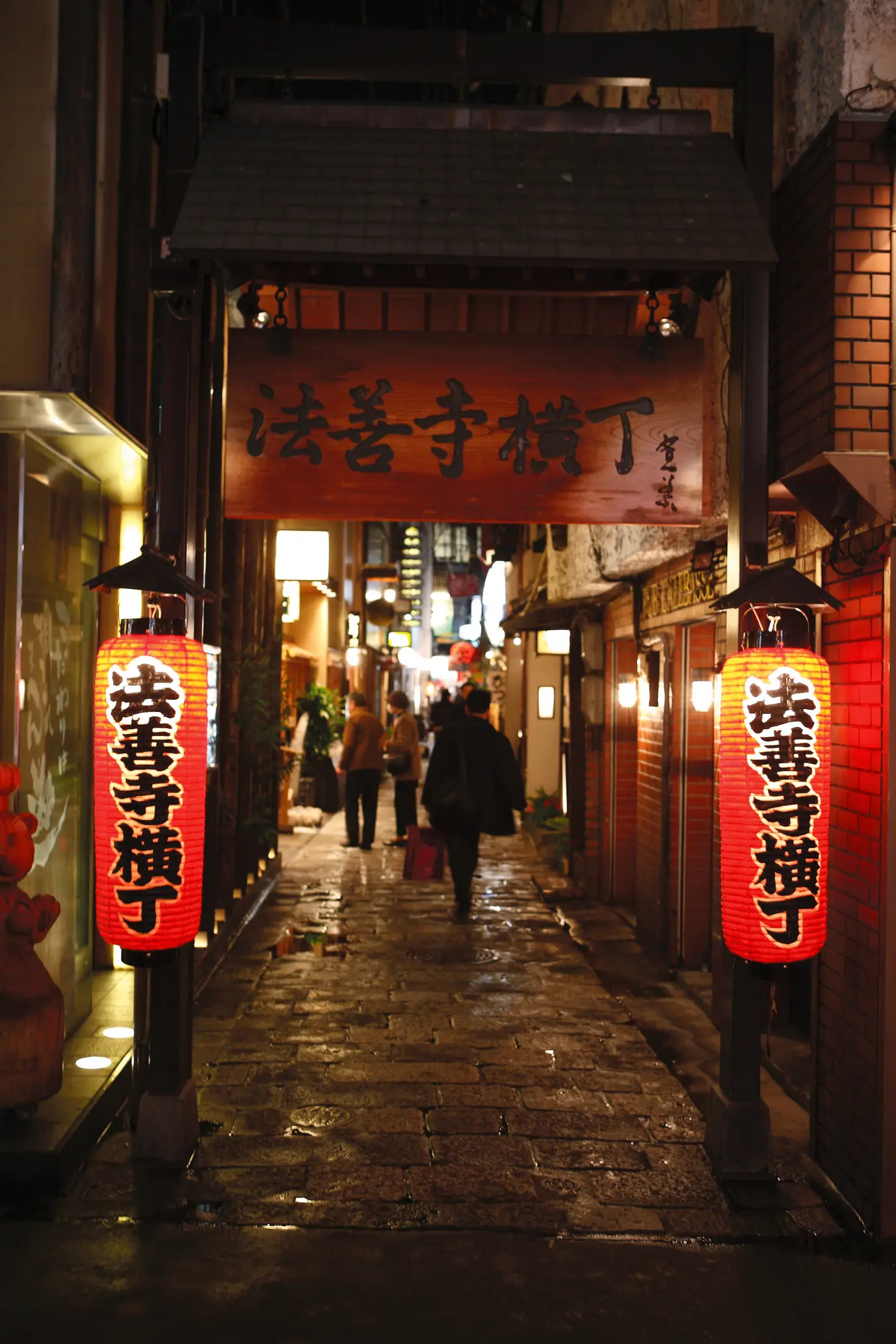 雨に濡れた石畳がしっとりとした風情を演出する横丁の入口