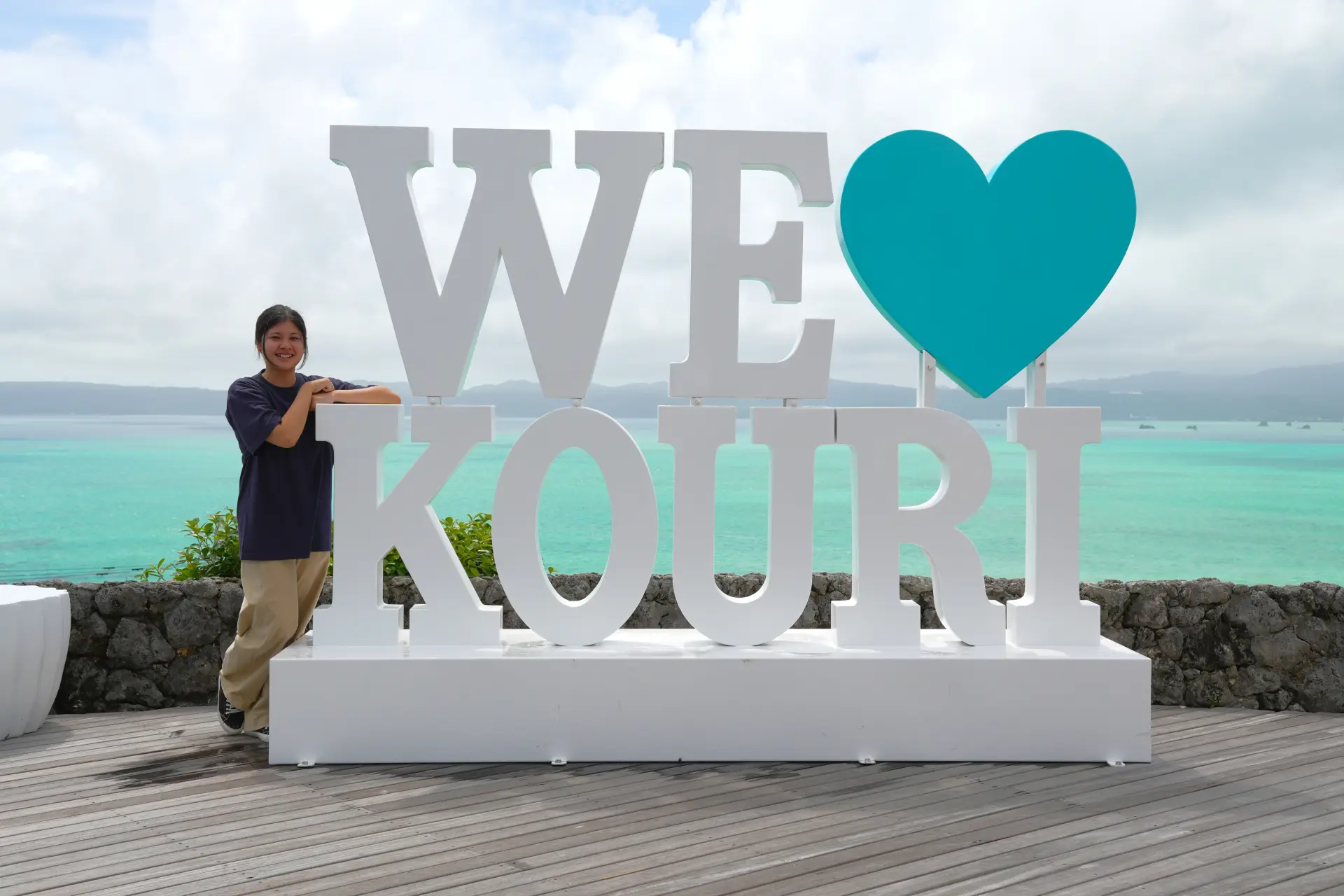 A souvenir photo with the “WE” and “KOURI” sculpture and its heart symbol