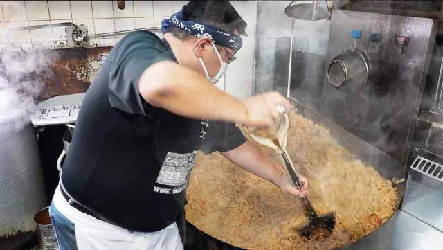 巨大な中華鍋とスコップで「地焼き」することで味がよくなじむ